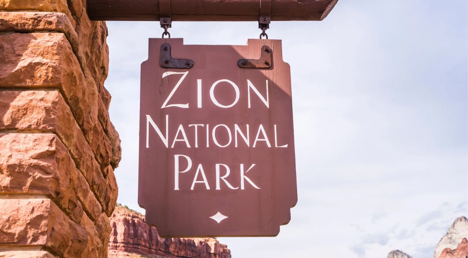 Hanging wooden Zion National Park sign against a pale sky