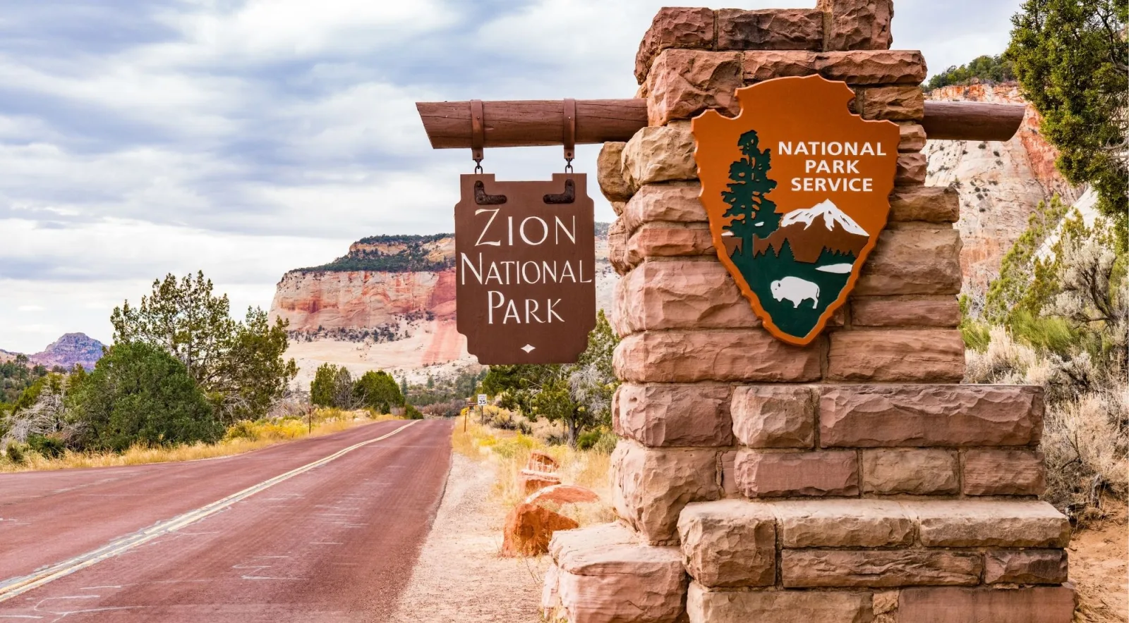 Stone Zion National Park entrance marker with the National Park Service arrowhead beside an empty road