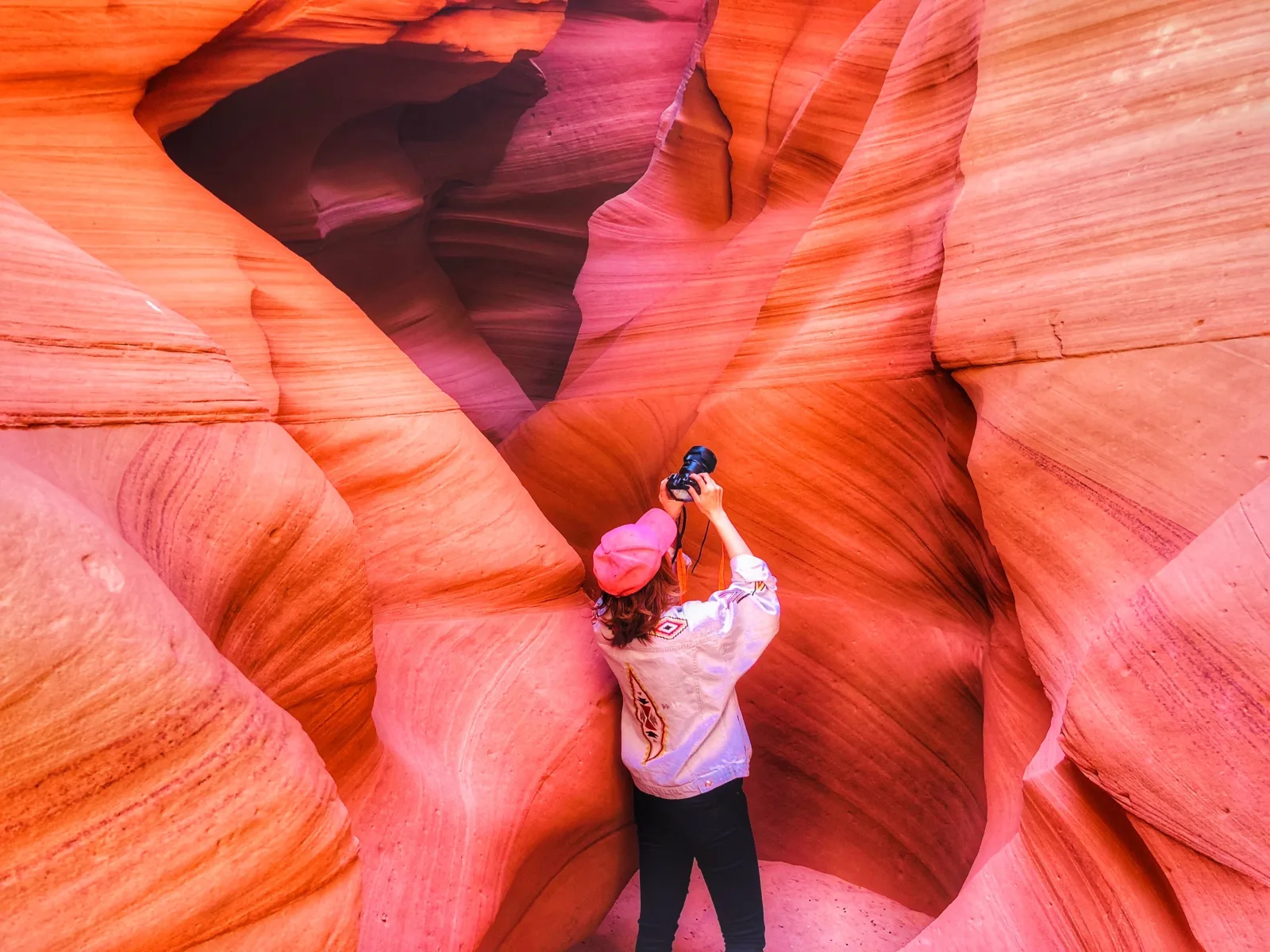 Photographer standing in a shaft of light inside the curved walls of Lower Antelope Canyon