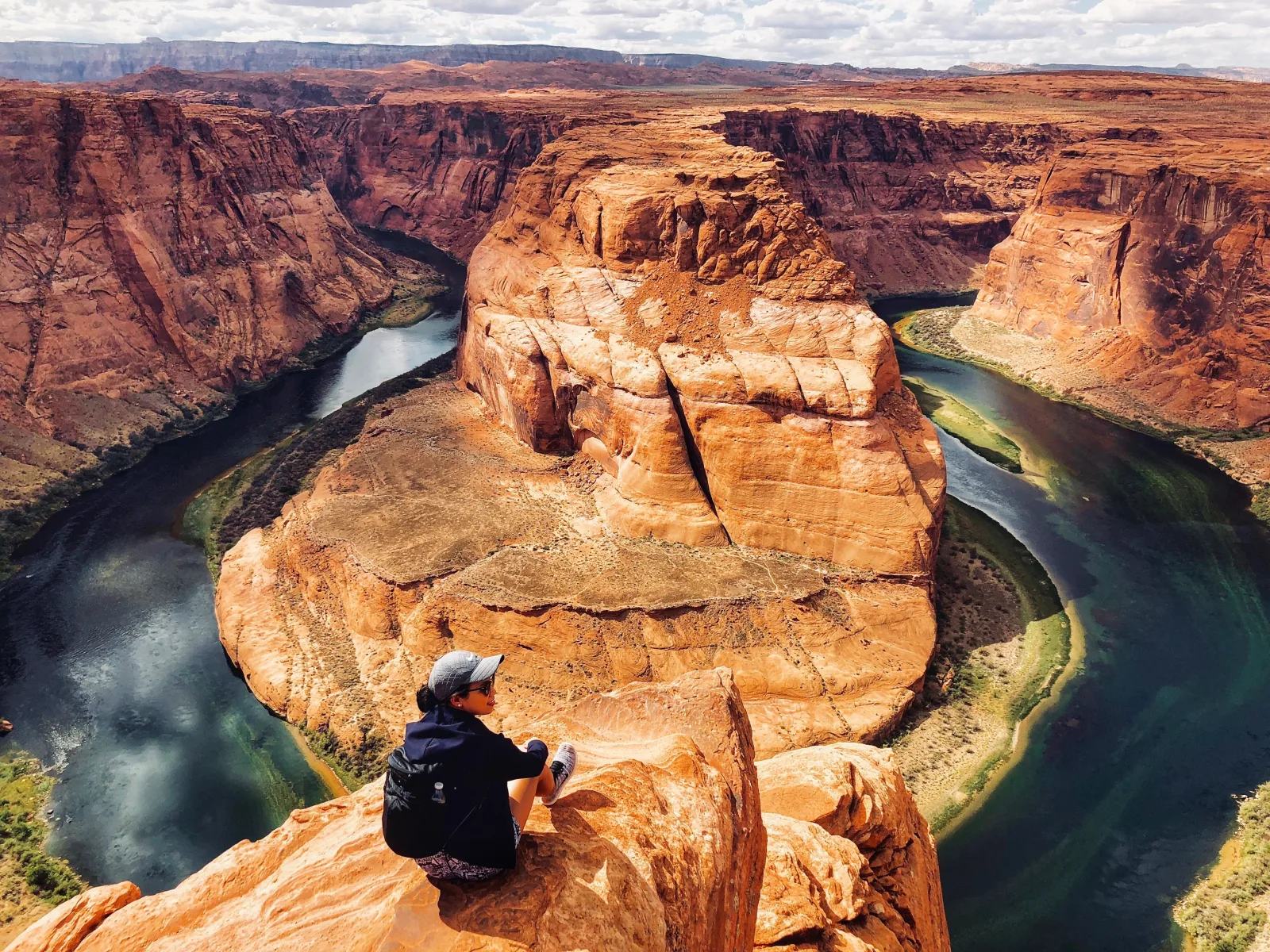 Horseshoe Bend from the rim, with a photographer at the edge above the Colorado River
