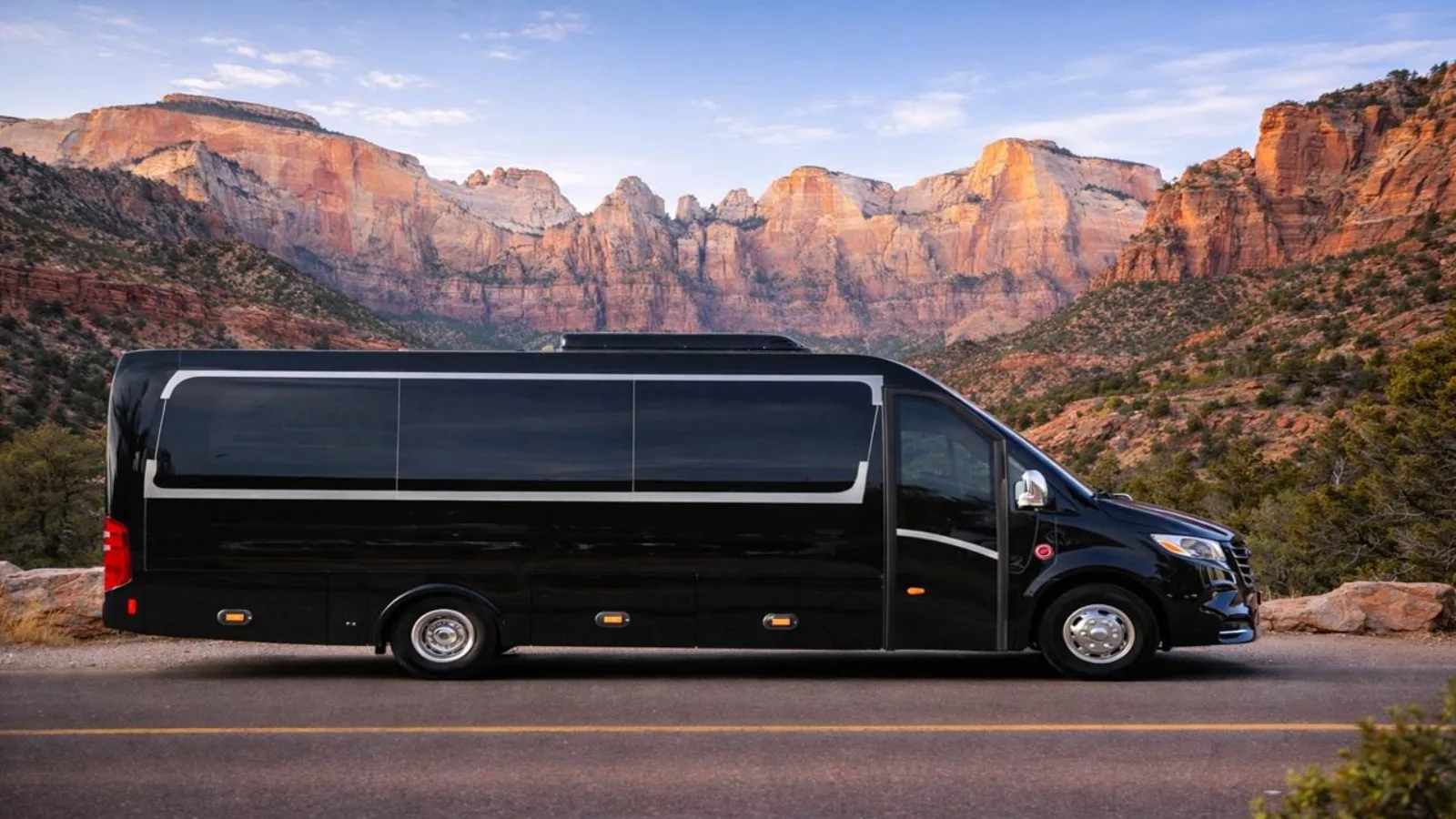 Black Mercedes Sprinter parked on the road with the Towers of the Virgin behind it