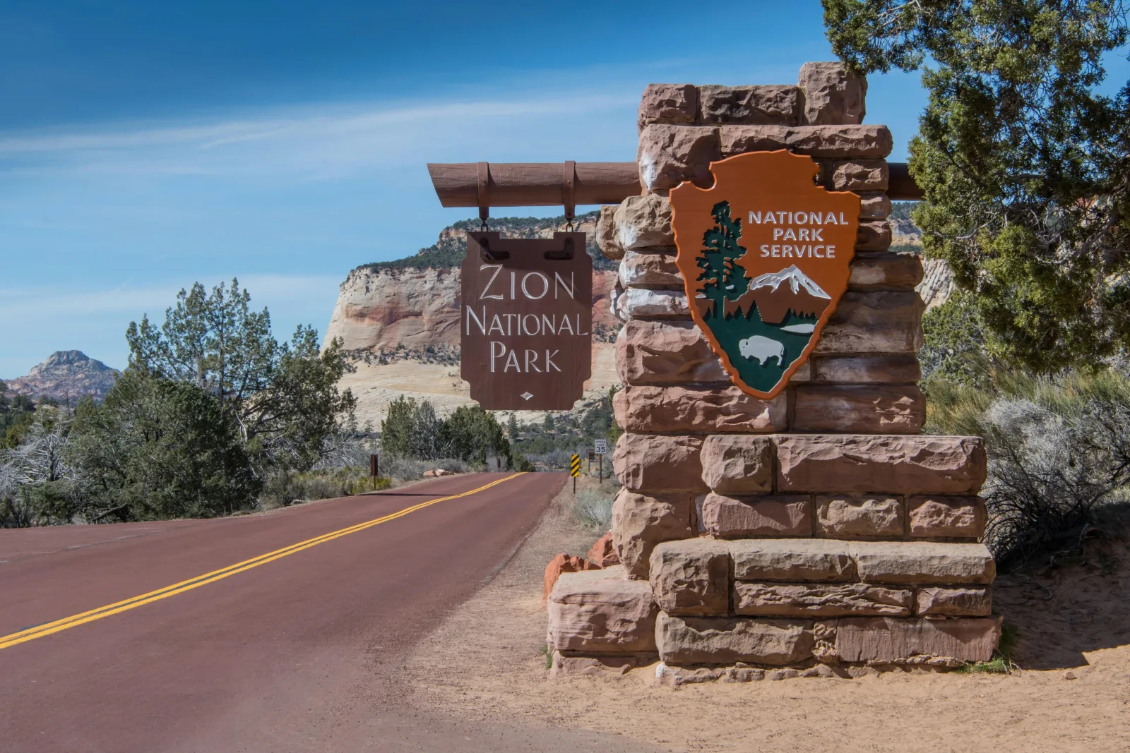 Stone Zion National Park entrance marker beside the highway into the park