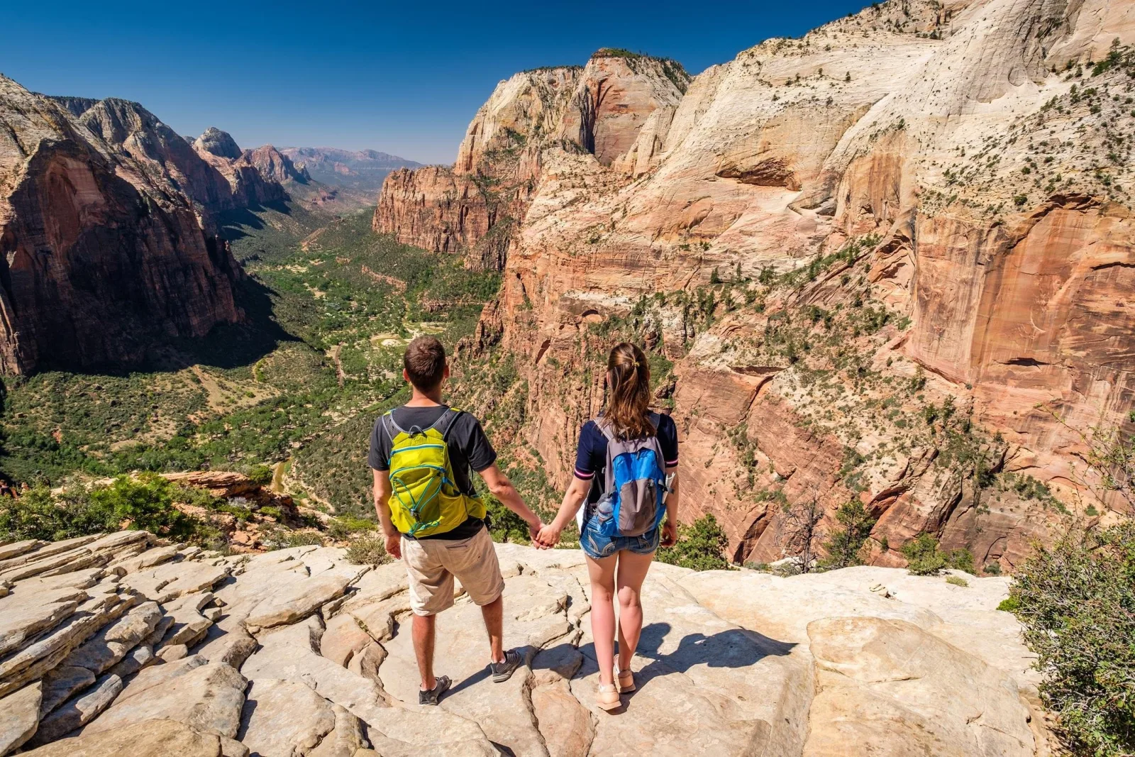 Pair of hikers crossing pale slickrock high above Zion Canyon