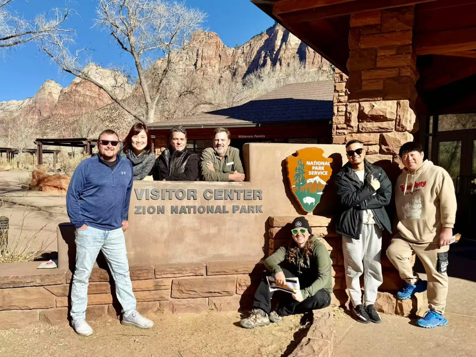 Small tour group photographed at the Zion National Park Visitor Center sign